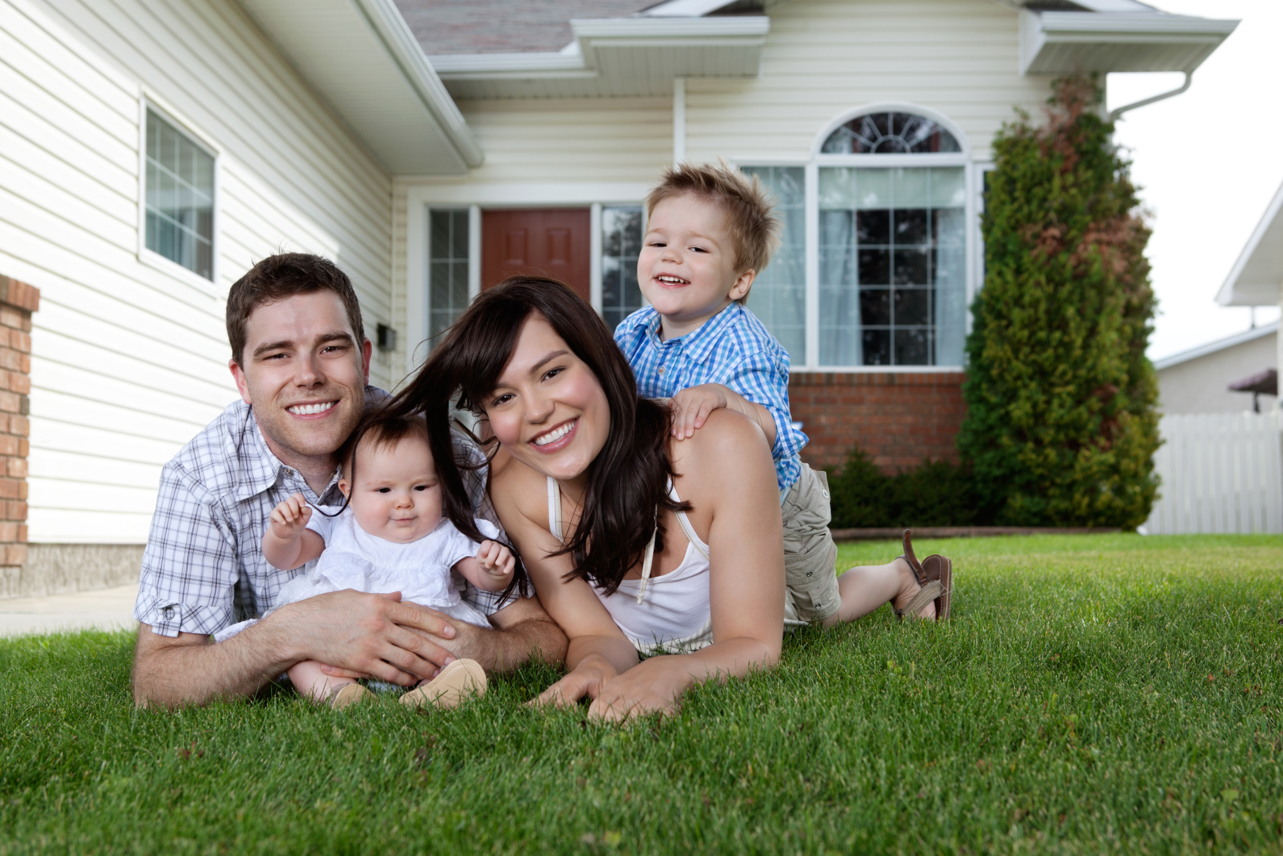 Young family smiling in front of house